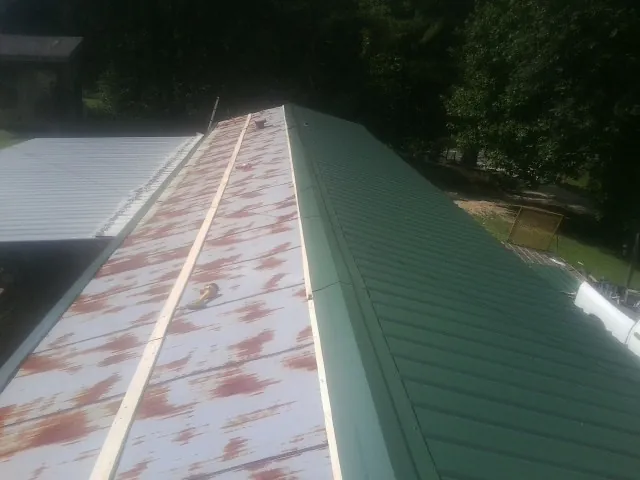 Old rusted panels beside newly installed green metal roofing — Wind Damage Roof Repair by Roofing Brothers in Smithtown