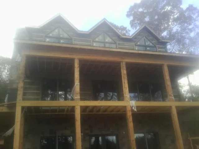 Dormers and porch framing on a large log home under construction — Roof Coating work by our crew in Smithtown
