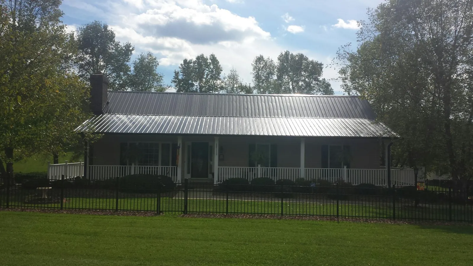 Gray metal roof on a brick ranch with a full width front porch — Gutter Guard Installation work by our crew in Smithtown