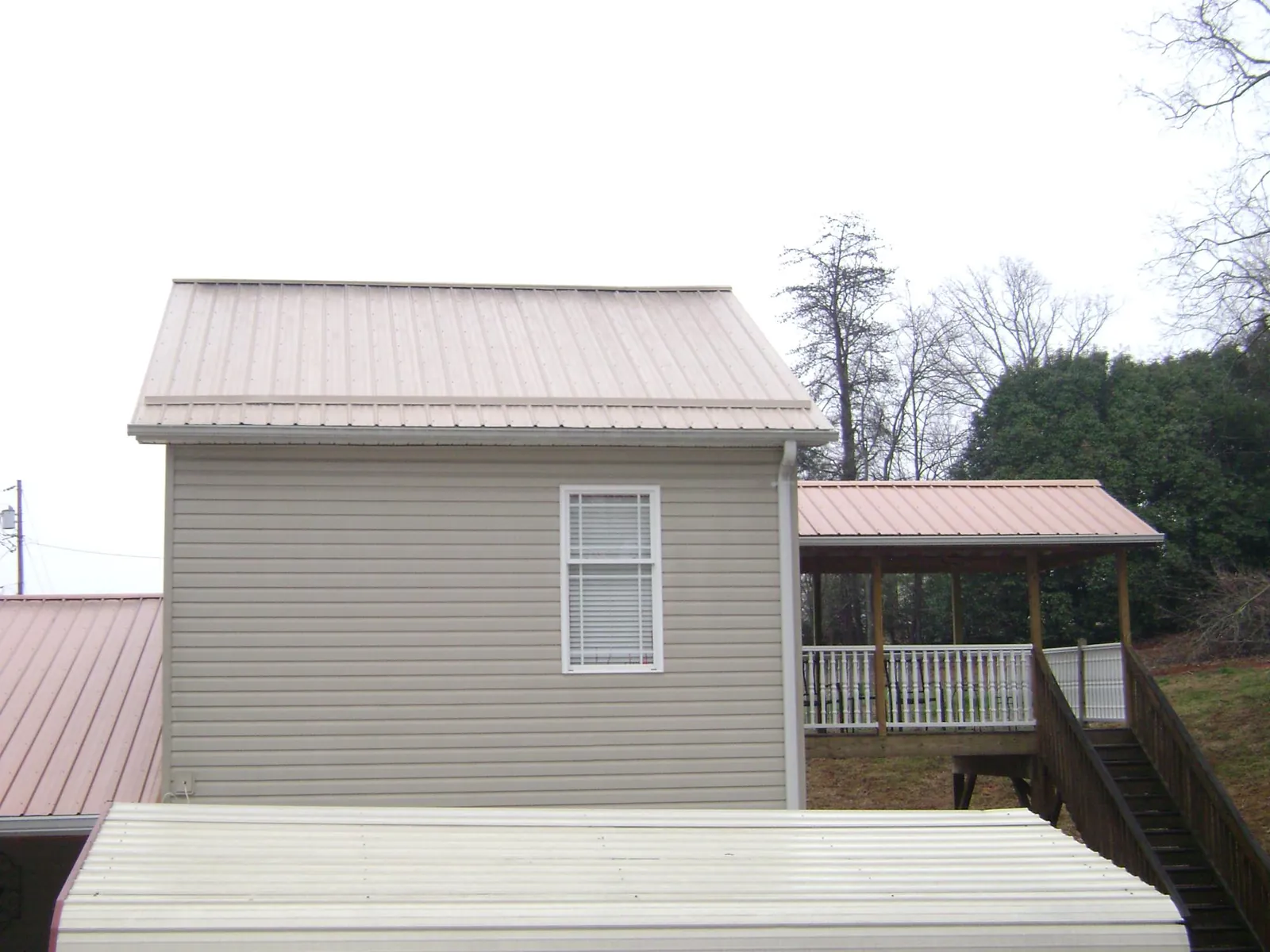 Tan metal roofs on a two story addition and attached porch, from a Roof Replacement job in Smithtown